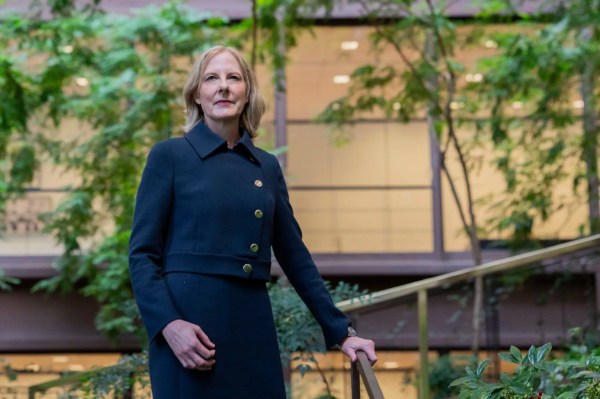 Ford Foundation president Heather Gerken in a navy coat with gold buttons standing in the foundation's atrium garden.
